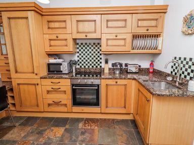 A kitchen with wooden cabinets and appliances at No9 Budle Sands Bamburgh