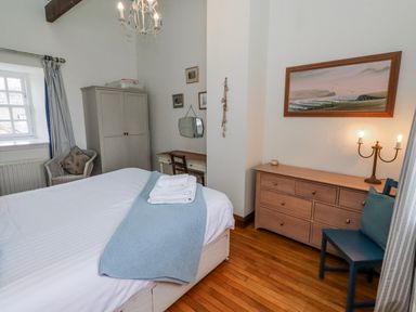 A bedroom with a bed, dresser, and chairs at No9 Budle Sands in Bamburgh