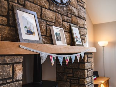 A stone fireplace with framed pictures on the mantel and a bunting hanging at Harbour Lights House in Seahouses