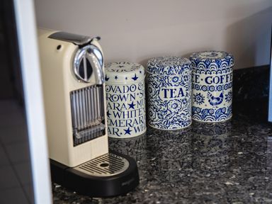 A coffee machine and three ceramic containers labeled sugar tea and coffee on a kitchen countertop at Harbour Lights House in Seahouses