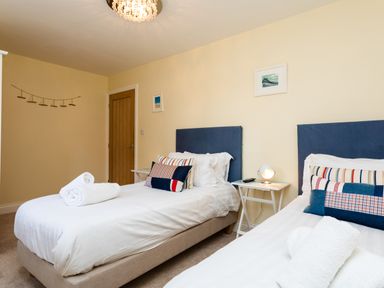 A bedroom with two single beds side by side each with blue headboards and striped pillows at Harbour Lights House in Seahouses