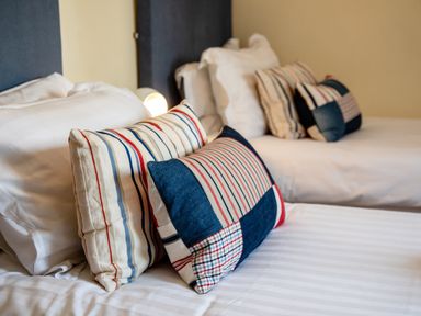 Two beds with white linens and striped pillows at Harbour Lights House in Seahouses