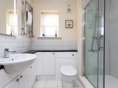 A bathroom with a sink toilet shower cabinet and window at Harbour Lights House in Seahouses