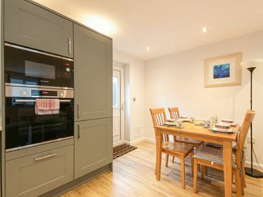 A kitchen with built in ovens and a wooden dining table with four chairs at Braidcarr Cottage in Seahouses