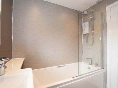 A bathroom with a bathtub shower combo sink and faucet at Braidcarr Cottage in Seahouses