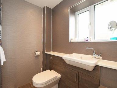 A bathroom with a toilet sink and window at Braidcarr Cottage in Seahouses