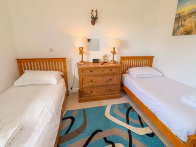 A bedroom with two beds and a dresser at Spindrifter in Beadnell