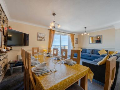 A dining and living room with a yellow tablecloth on the table and blue sofas at Lobster Lodge in Seahouses