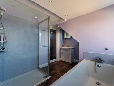 A bathroom with a shower enclosure a bathtub a sink and a mirror at Lobster Lodge in Seahouses