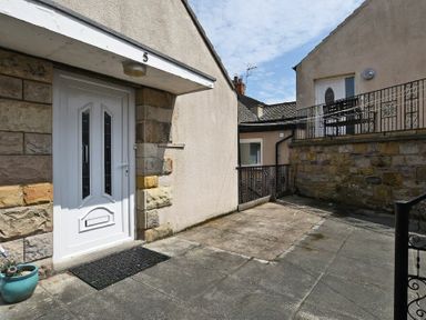 An outdoor area with a white door marked number 5 and stone walls at Lobster Lodge in Seahouses
