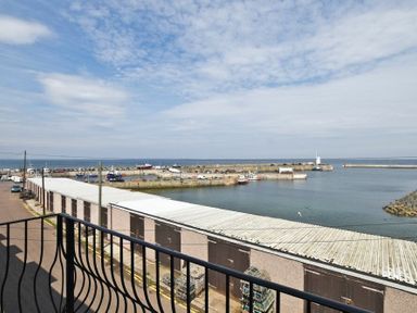 A view of a harbor with boats docks and storage buildings seen from a balcony at Lobster Lodge in Seahouses