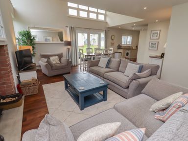 A living room with a sofa, coffee table, and armchairs at The Beach Hut in Beadnell