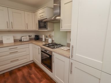 A kitchen with a gas stove and microwave at The Beach Hut in Beadnell
