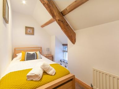A bedroom with a single bed wooden beams and a bedside table with a lamp at East Havers in Alnwick