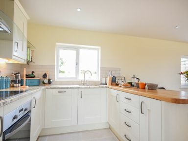 A kitchen with white cabinets a countertop with kitchen utensils and a window at Rock Lodge in Alnmouth