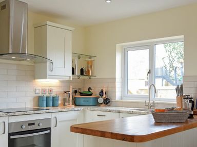 A kitchen with white cabinets and a wooden countertop at Rock Lodge in Alnmouth