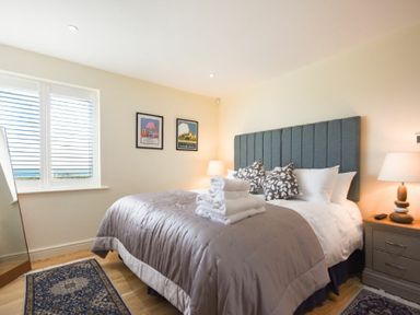 A bedroom with a double bed bedside table lamps and framed pictures on the wall at Rock Lodge in Alnmouth
