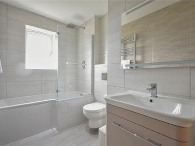 A bathroom with a bathtub shower combination toilet sink and mirror at Rock Lodge in Alnmouth