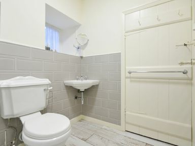 A bathroom with a toilet sink and a door with hooks at West End Cottage in Embleton