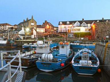A harbor with several fishing boats docked and buildings in the background at The Bolthole (Seahouses) in Seahouses