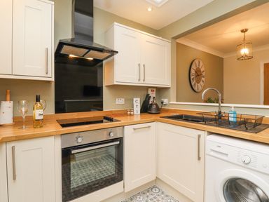 A kitchen with an oven stovetop sink washing machine and cabinets at The Bolthole in Seahouses
