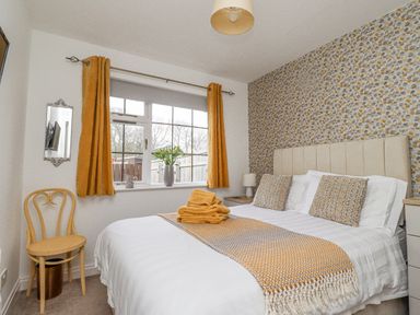 A bedroom with a bed a chair and a window with yellow curtains at The Bolthole (Seahouses) in Seahouses
