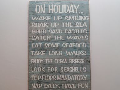 A wooden sign with holiday advice text on a wall at The Bolthole (Seahouses) in Seahouses