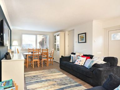A living room with a blue sofa and wooden dining table with chairs at Stones Throw in Beadnell