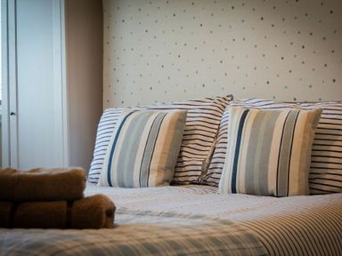 A bed with striped pillows and folded towels in a bedroom at Stones Throw in Beadnell
