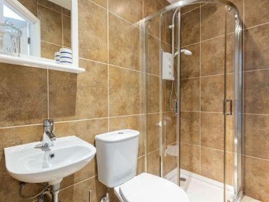 A bathroom with a sink a toilet and a shower enclosure at Stones Throw in Beadnell