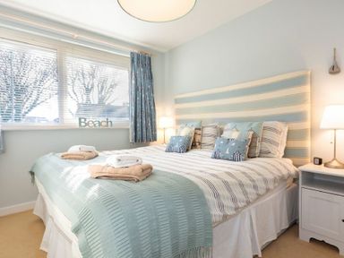 A bedroom with a double bed with striped headboard and folded towels on the bed at Stones Throw in Beadnell