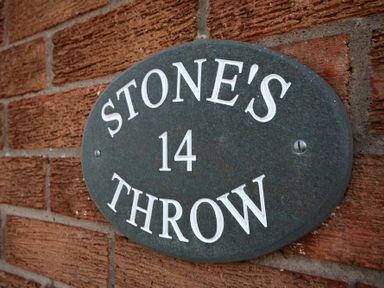 A stone plaque with the text Stones Throw 14 on a brick wall at Stones Throw in Beadnell