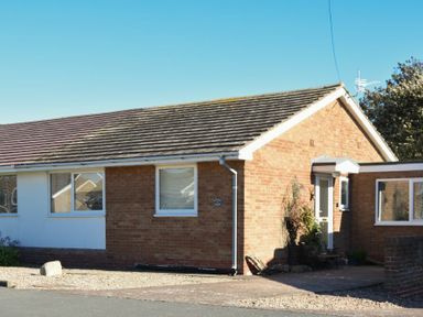 A single story brick house with a tiled roof and a small front garden at Stones Throw in Beadnell