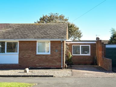 A brick house with two windows and a driveway next to a green garage door at Stones Throw in Beadnell