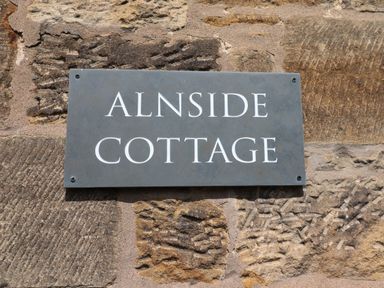 A sign reading Alnside Cottage mounted on a stone wall at Alnside Cottage in Alnmouth