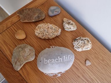 A wooden table with various decorative stones including one engraved with beach life at Riverside Lodge in Alnmouth