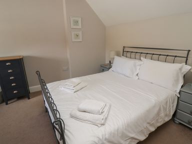A bedroom with a double bed with white linens and towels on it two bedside tables and a chest of drawers at Riverside Lodge in Alnmouth