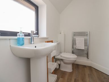 A bathroom with a sink a toilet a towel rack and a window at Riverside Lodge in Alnmouth