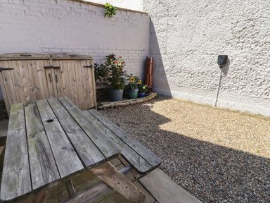 An outdoor area with a wooden picnic table garden storage cabinet and potted plants at Riverside Lodge in Alnmouth