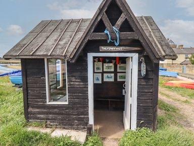 A small wooden hut with a pitched roof with an open door and pictures hanging inside at Riverside Lodge in Alnmouth