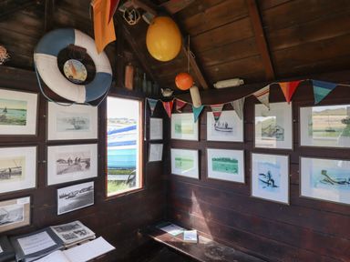 A wooden room with framed pictures on the walls a life ring a bench and nautical decorations at Riverside Lodge in Alnmouth