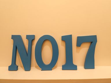 Blue block letters spelling No 17 against a beige wall at Number Seventeen in Amble