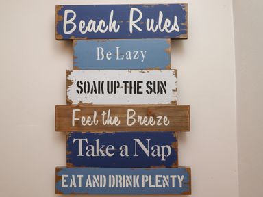 A wall sign with beach rules including be lazy soak up the sun feel the breeze take a nap eat and drink plenty at Number Seventeen in Amble