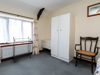 A room with a window with curtains a metal clothes rack a white wardrobe a white dresser and a wooden chair at Swallows Cottage nr Warkworth in Acklington