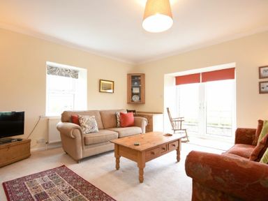 A living room with two sofas a wooden coffee table a TV and rocking chair at Dunrovin in Beadnell