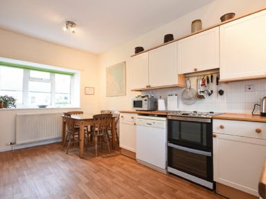 A kitchen with a wooden dining table and chairs a stove microwave dishwasher and cabinets at Dunrovin in Beadnell