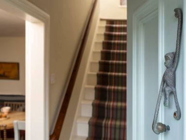 A hallway with a staircase and a decorative handle at Sandpiper (Alnmouth) in Alnmouth