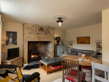 A living room with a fireplace and furniture at Sandpiper in Alnmouth