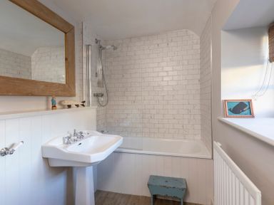A bathroom with a bathtub and sink at Sandpiper (Alnmouth)
