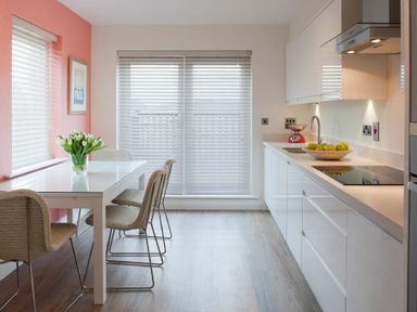 A kitchen and dining area with a white table and four chairs a bowl of green apples on the counter and tulips on the table at Portside in Seahouses